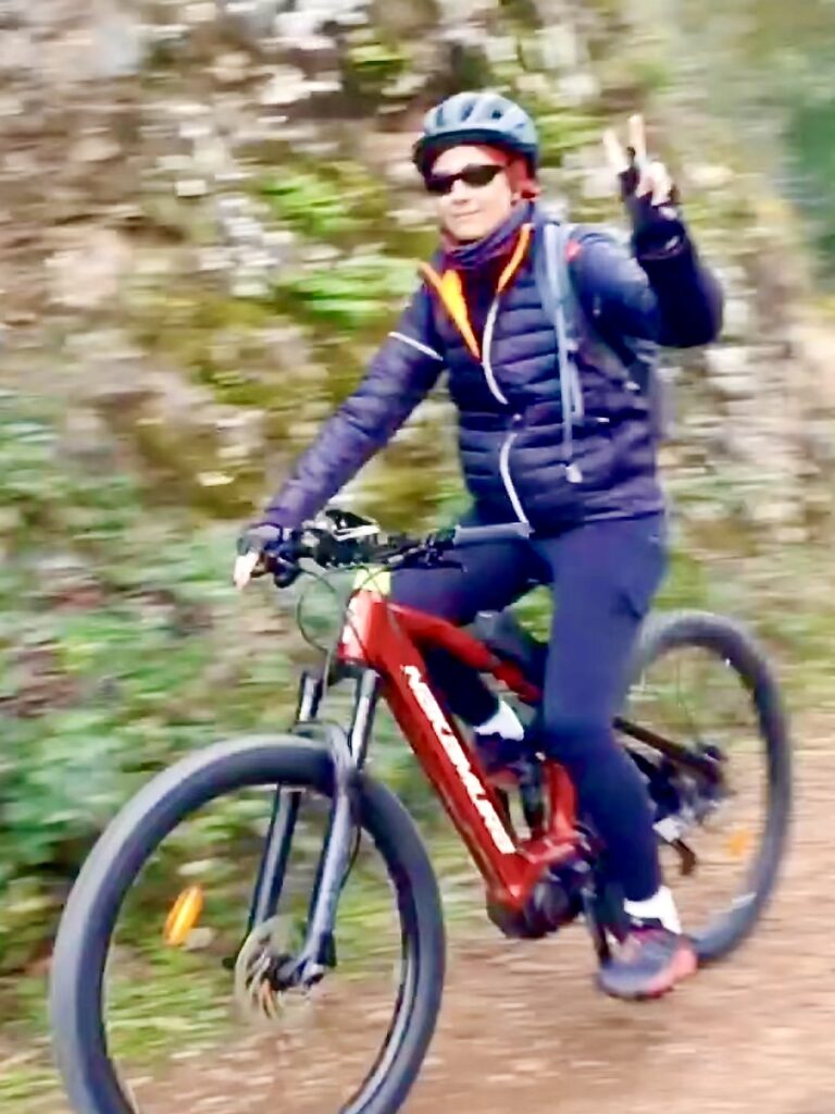 Me on my new e-mountain bike doing the peace sign. There is motion blur around me.