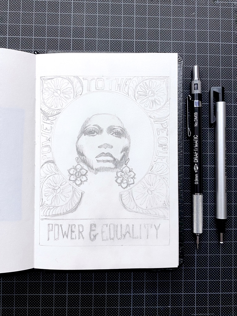 Very detailed pencil sketch on an open artbook of the face of Angela Davis, ornate flowers and lettering. The mechanical pencil and eraser pen are on the cutting mat.
