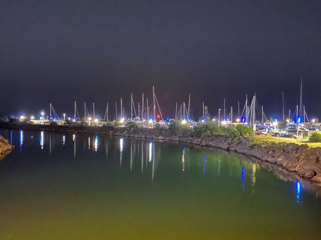 Night shot of the white masts of sailboats reflected in water