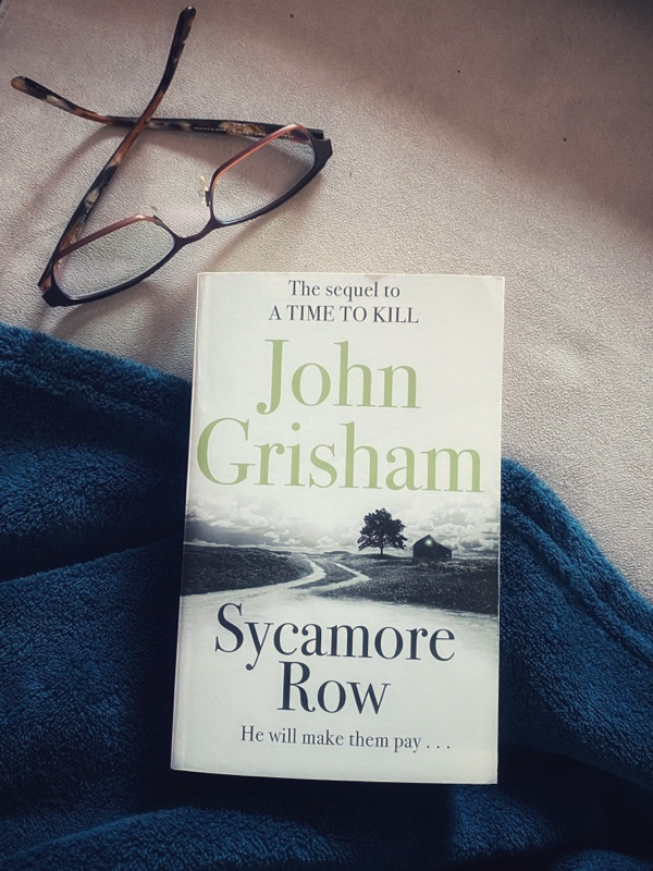 Book on a blue blanket next to my reading glasses.
