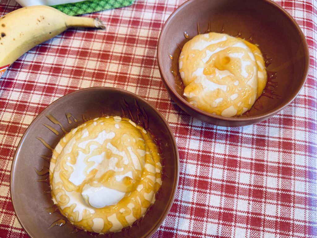 Two bowls filled with cottage cheese and coated with honey