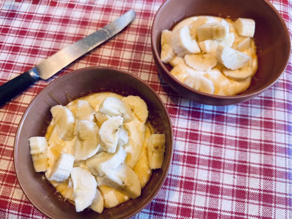 Two bowls with cottage cheese, coated with honey and filled with banana chunks