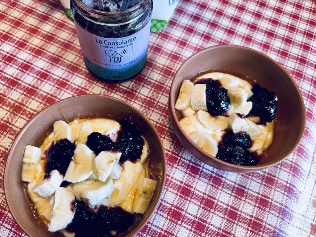 Two bowls with cottage cheese, coated with honey, filled with banana chunks and three lumps of jam